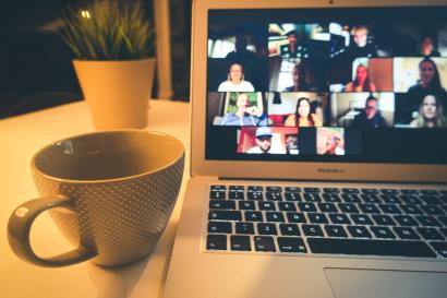 Coffee cup next to a laptop with virtual meeting displayed