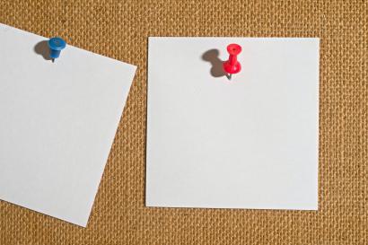 White square papers pinned to cork board