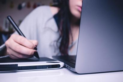 Student working on laptop and writing.