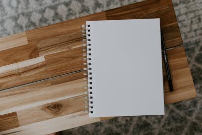 A blank page of a notebook on top of a wooden table.