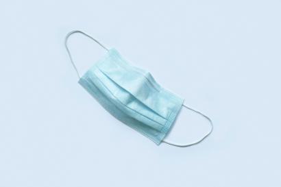 Photo of a blue-green disposable face mask on a light blue background
