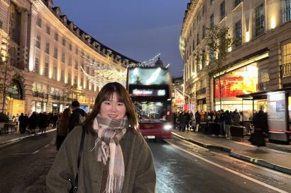 A student poses on the high street of Central London at night