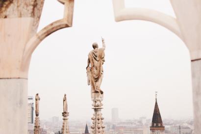 an artistic shot of a statue atop Duomo di Milano
