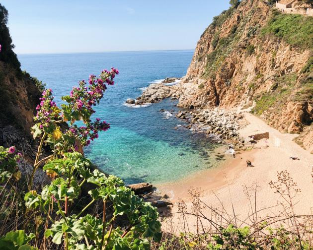 a secluded beach surrounded by natural cliffs and clear, blue waters