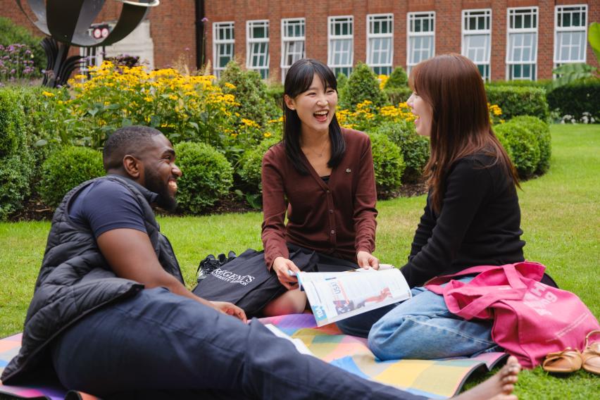Three students lounging in courtyard of Regent's University London.