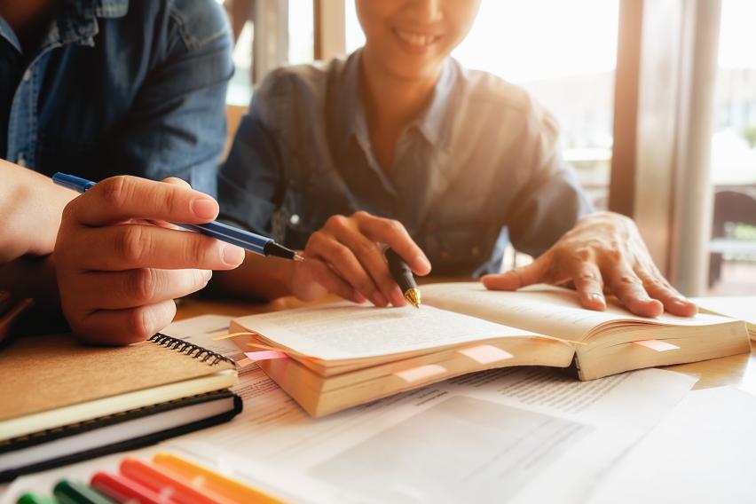 students working at a desk in front of an open book