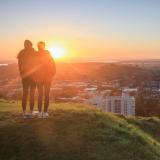two students watch the sunset atop Mount Eden in Auckland