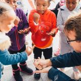 a student plays rock, paper, scissors with children in Cape Town