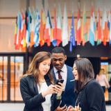 students checking their phone in front of the European Council