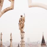 an artistic shot of a statue atop Duomo di Milano