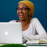 a student smiling while using their laptop