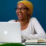 a student smiling while using their laptop