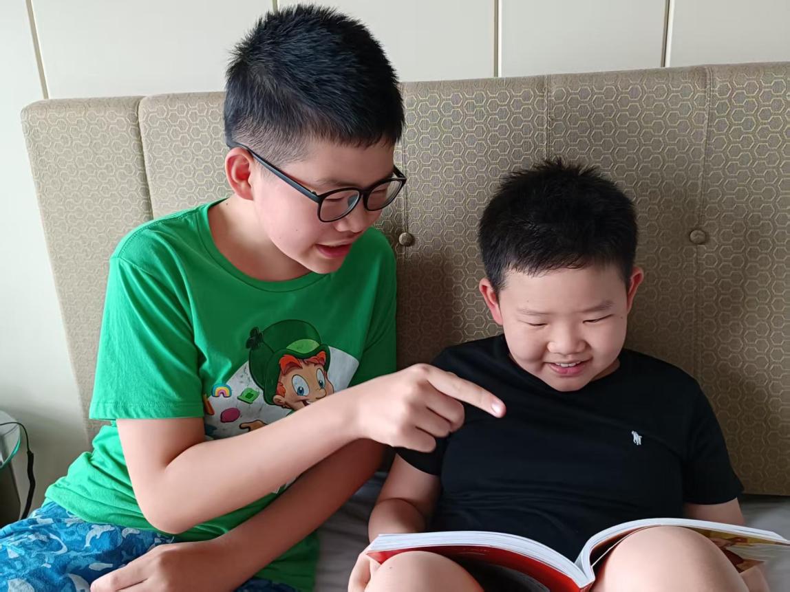 Staff member Gorden Xie's older son helping his younger brother read a book.