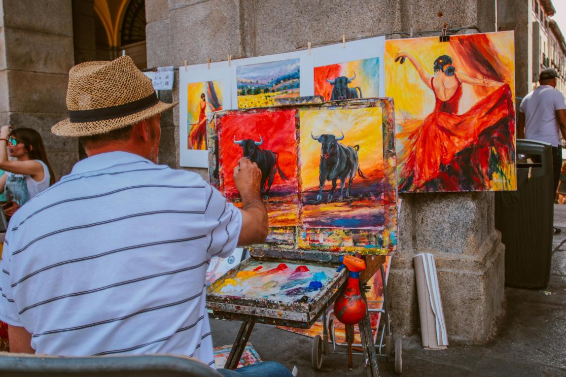 Painter on Spanish street working on paintings of bulls and Flamenco dancers