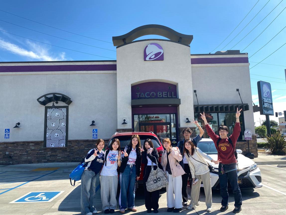 Group of students excited in a Taco Bell parking lot.