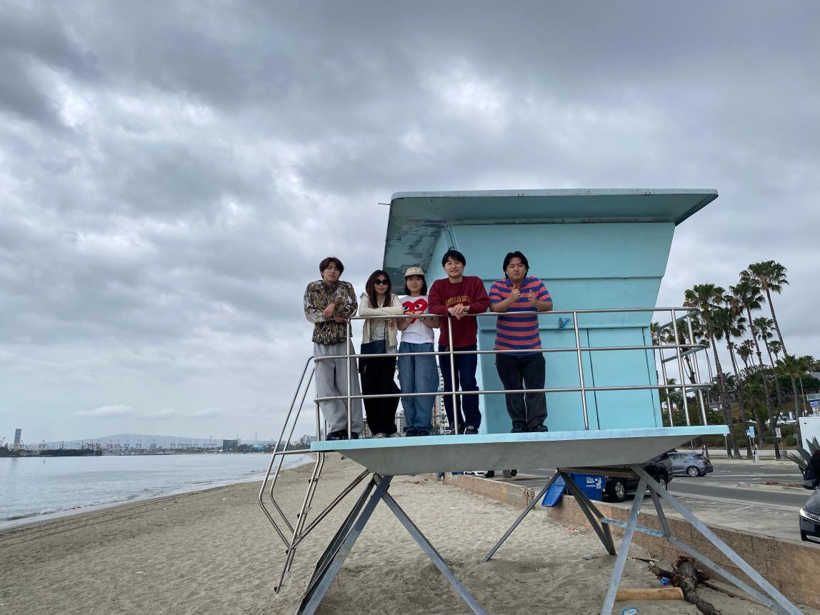 Five students standing at a lifeguard tower on a Long Beach beach.