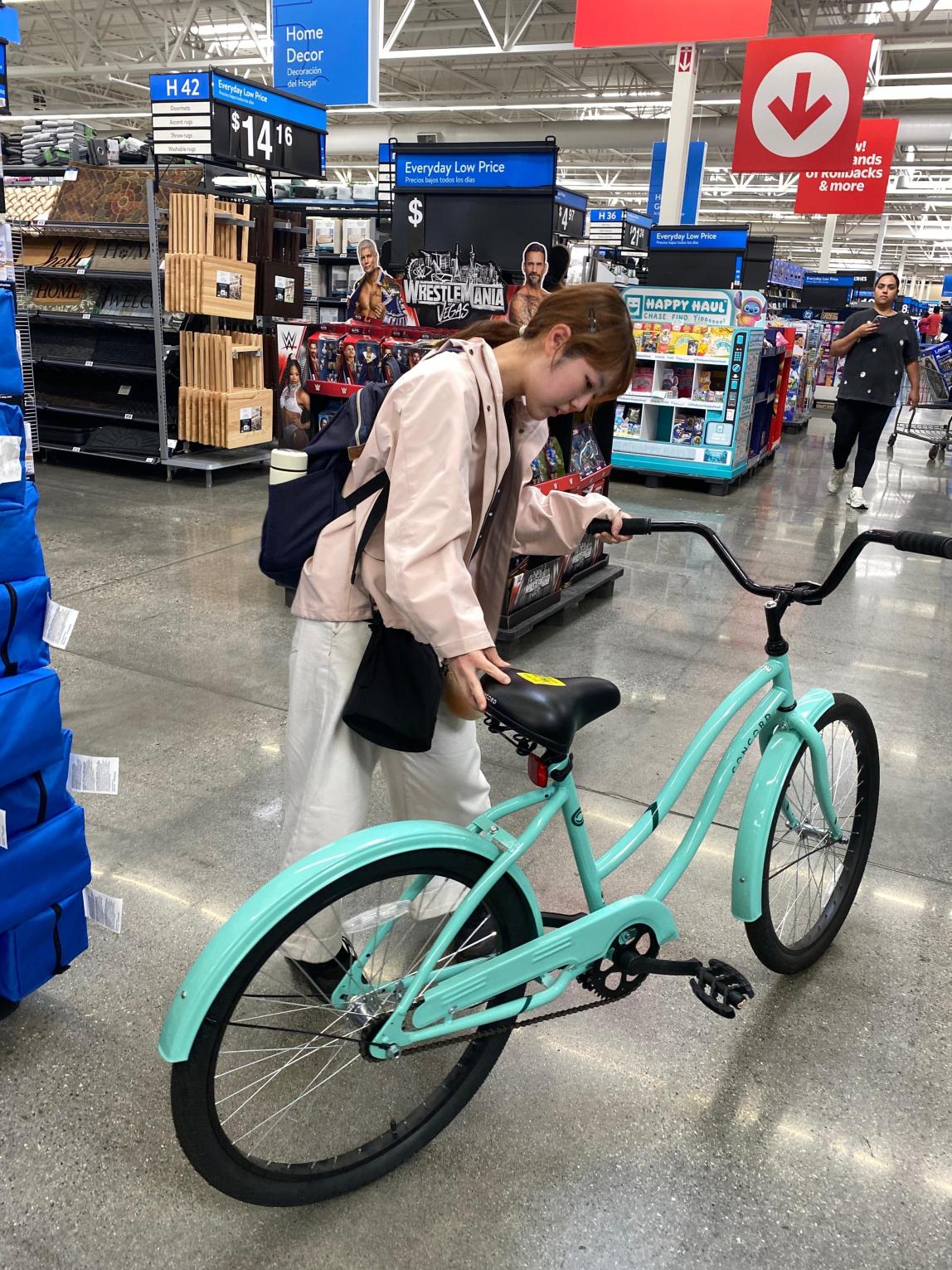 Female student inspecting a blue cruiser bicycle inside of Walmart.