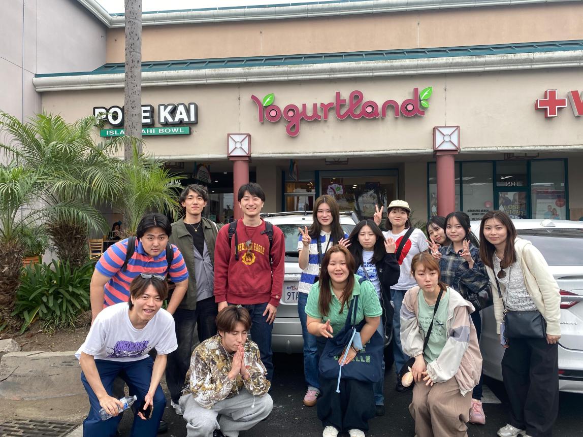 Students posing outside of a strip mall's Yogurtland.