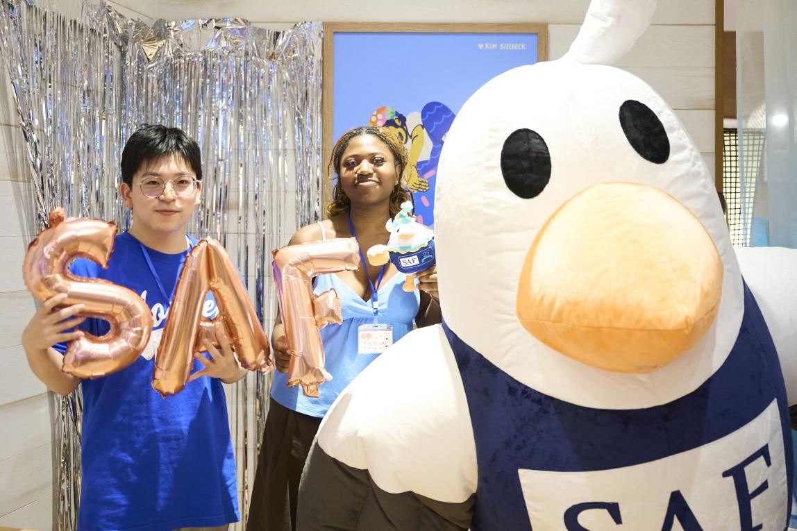 2 students take a photo with the SAFFY mascot.