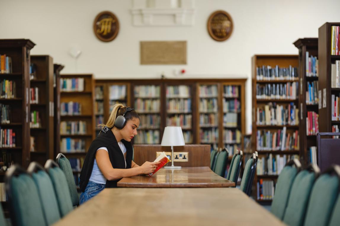 Student listening to music and reading in library of Regent's University London. 