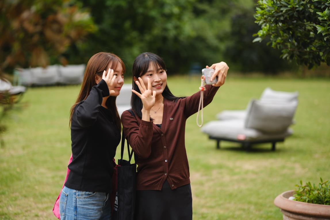 Two students taking a selfie in a park. 