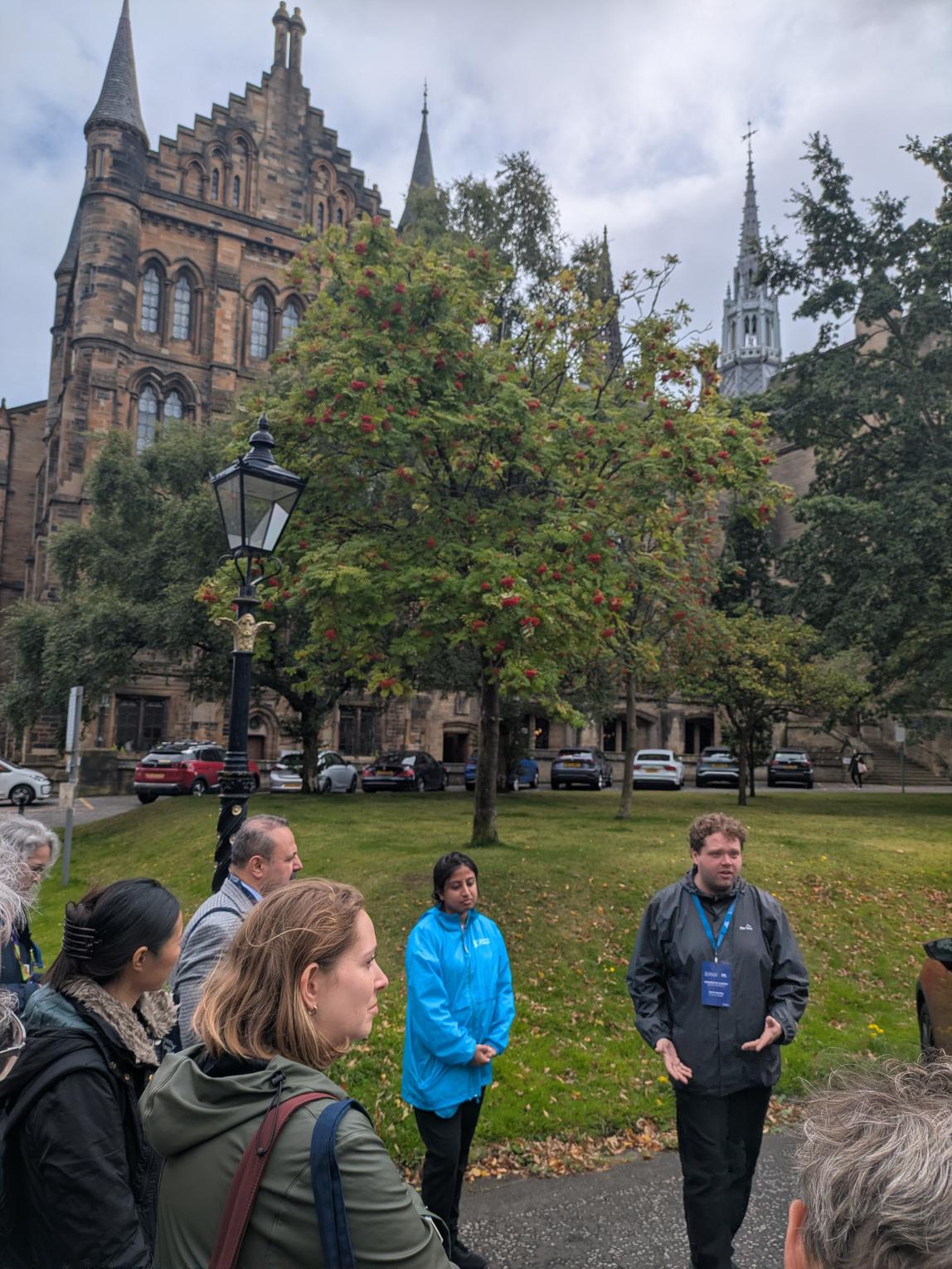 Tour guide presenting to a group in front of the University of Glasgow.