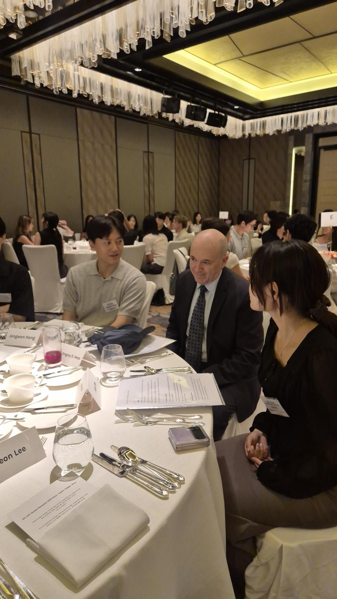 Dr. Greg Hess sitting at his table with student alumni.