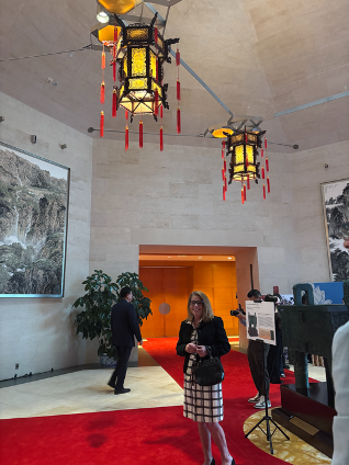 Carol Carmody at the 77th Anniversary PRC event entrance, standing under two ornate Chinese lanterns.