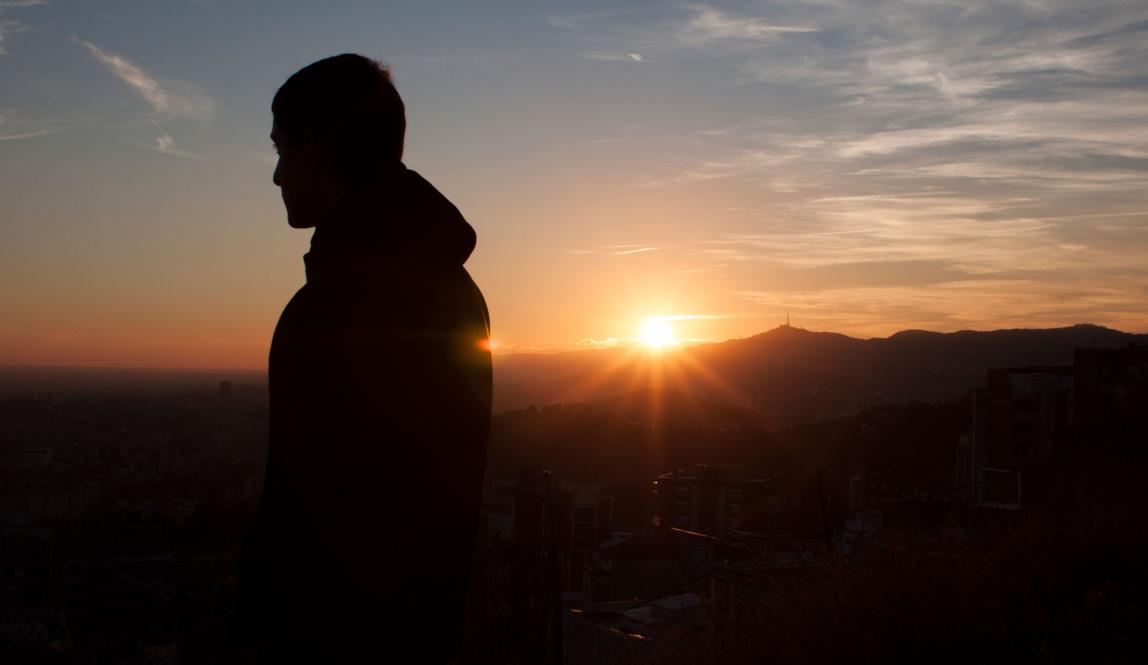 a student looks out over Barcelona from the Bunkers during sunset