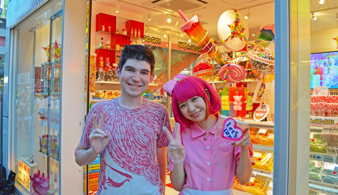 a student poses for a photo with a staff member at a candy store in Harajuku