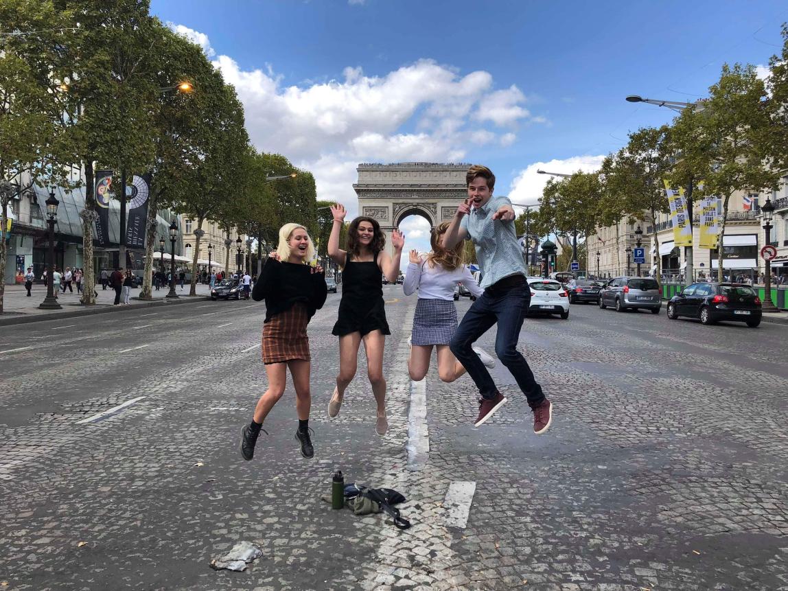 students jumping for a fun photo in front of arc de triomphe