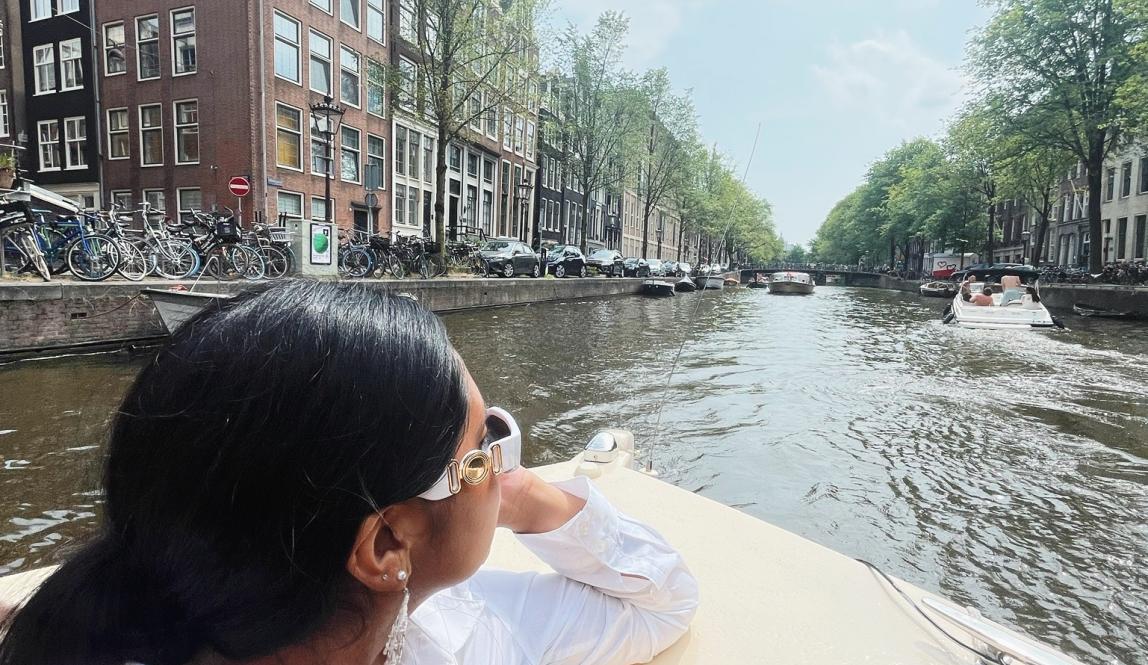 a student riding through the Amsterdam canals on a boat