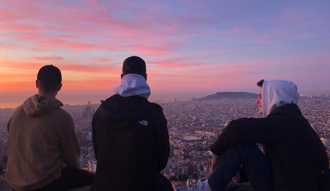 three male students look out over Barcelona from the Bunkers