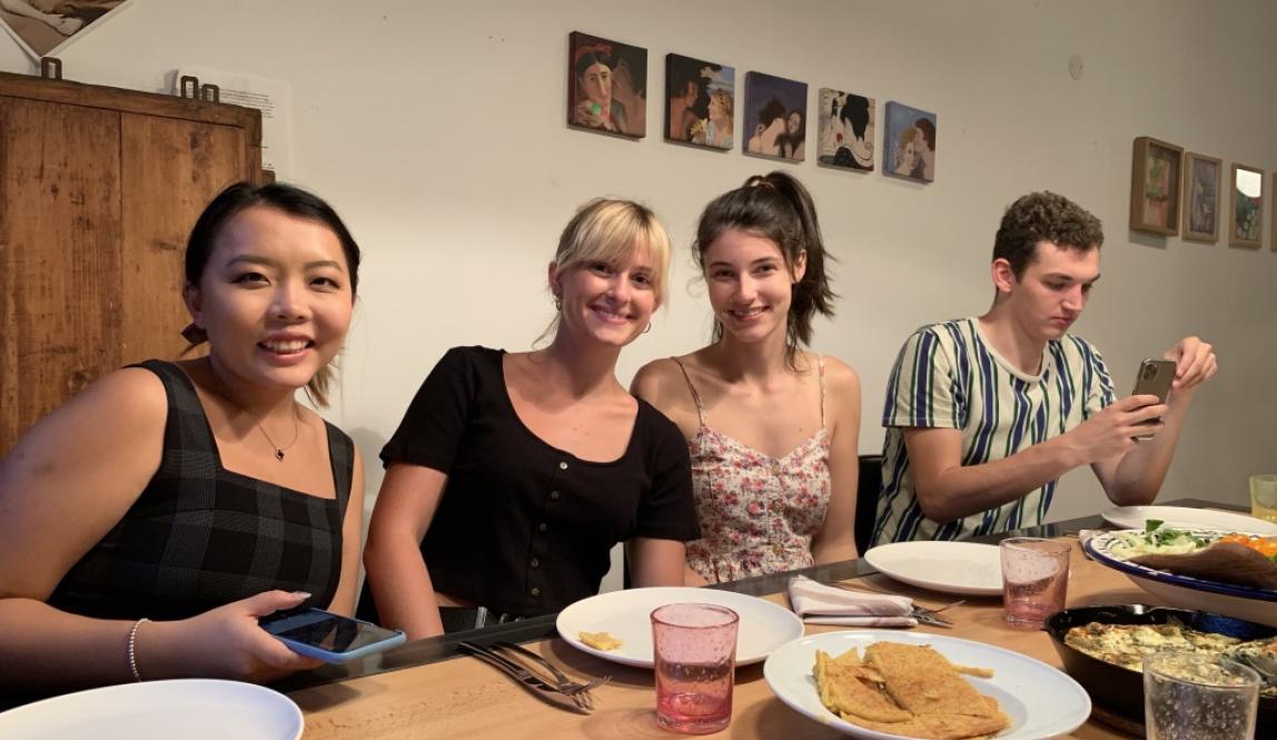 Students with their host mom seated around a dinner table at a homestay in Nice.