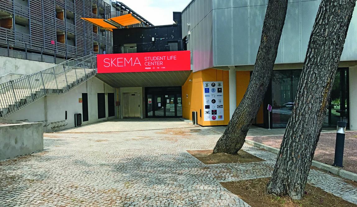 Outside of the SKEMA Student Center. There is a large staircase (left) and two large trees (right).