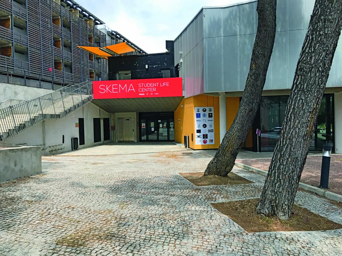 Outside of the SKEMA Student Center. There is a large staircase (left) and two large trees (right).