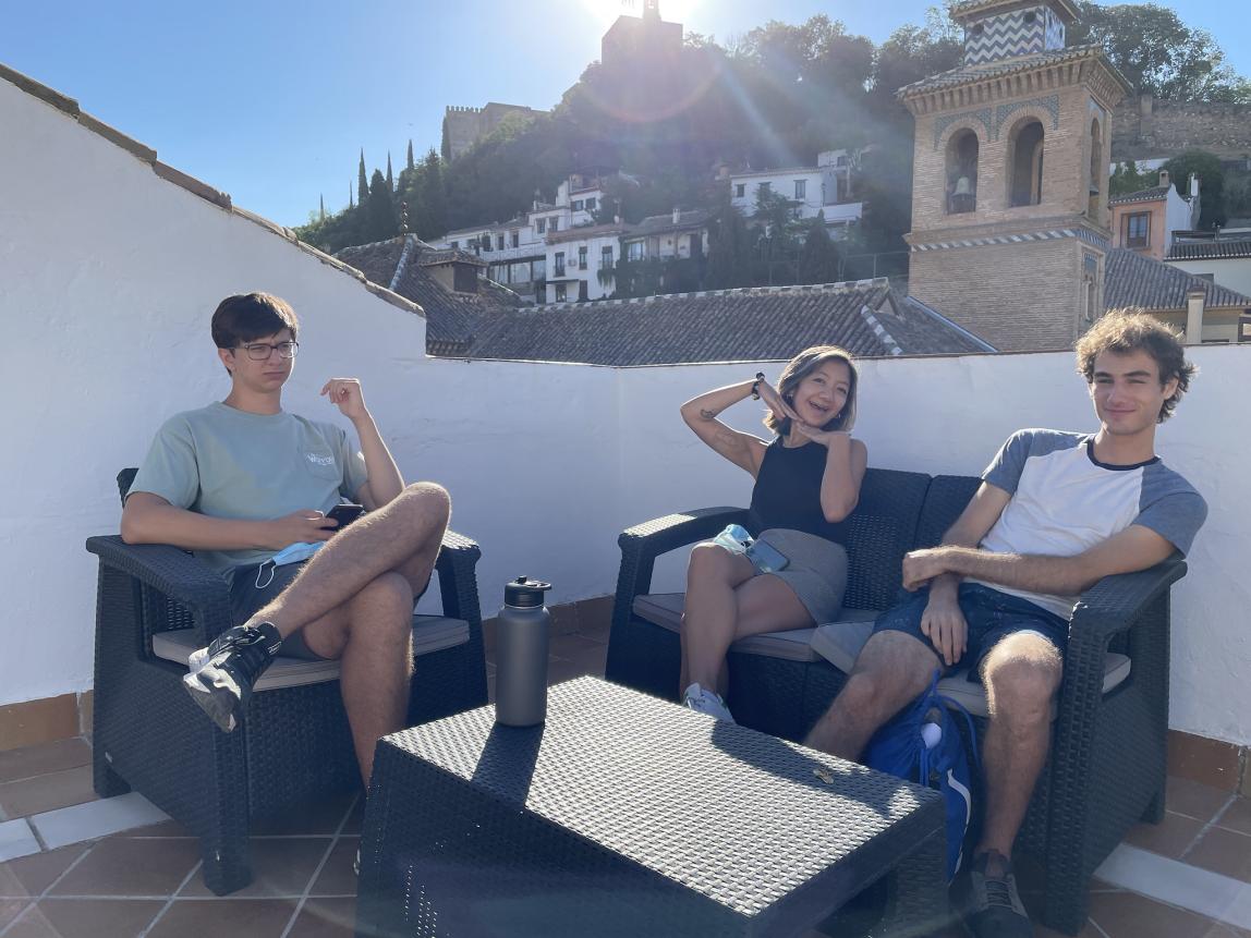 Three students sitting on the patio of the Granada Center with the sun shining behind them
