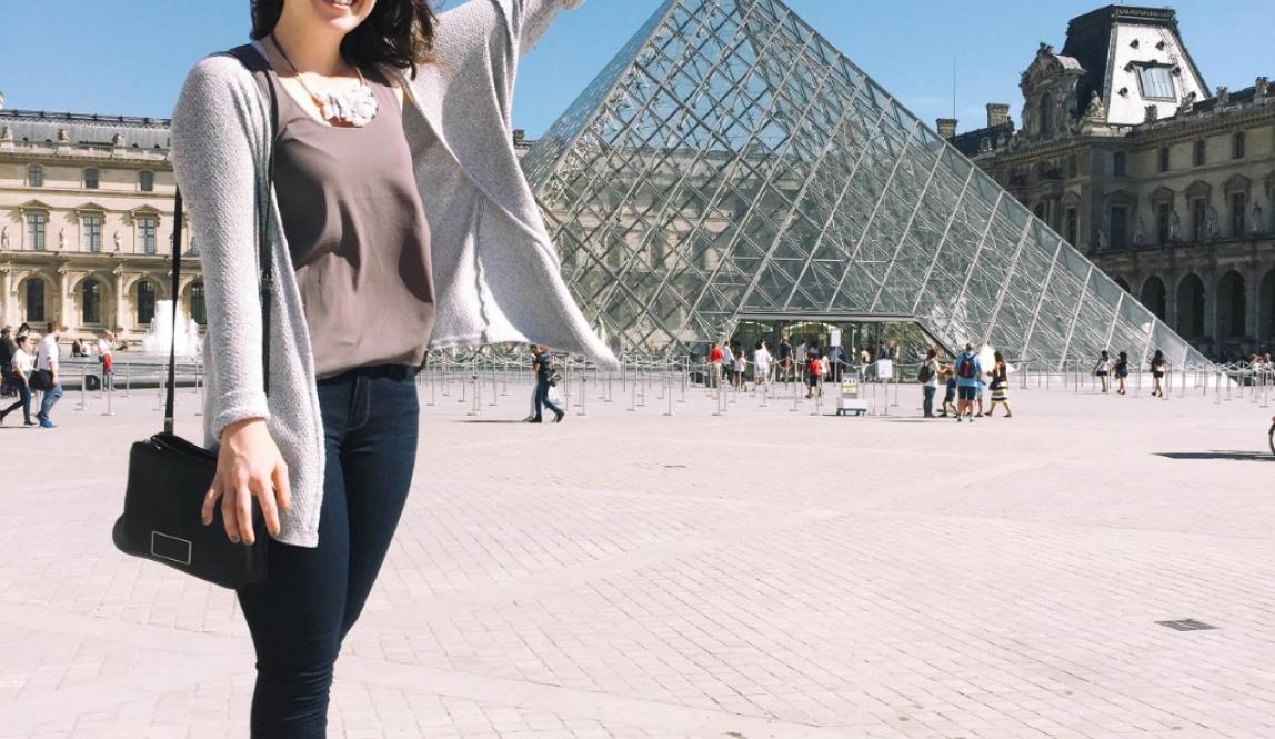 Student at an angle that looks like she is touching the top of the Louvre 