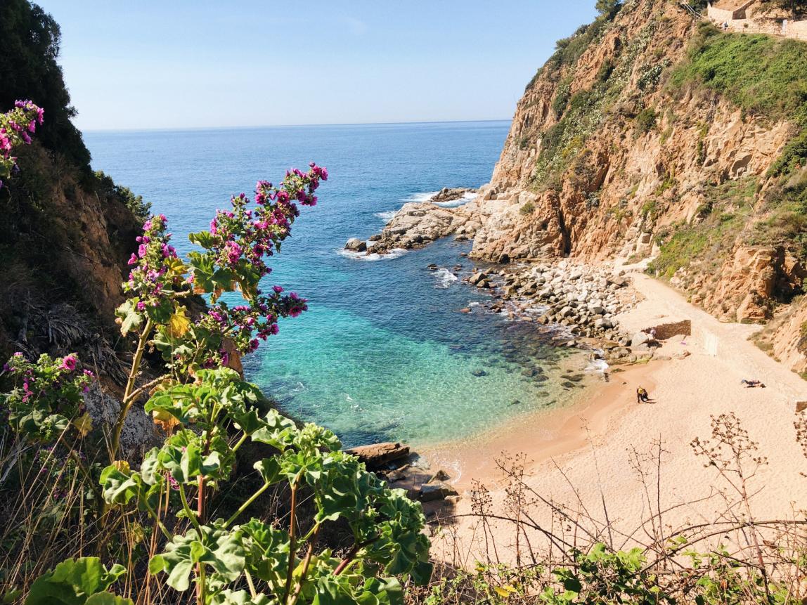 a secluded beach surrounded by natural cliffs and clear, blue waters