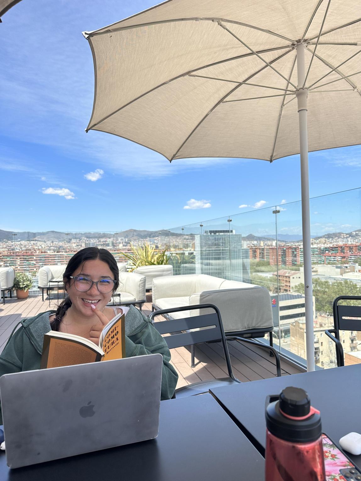 A student studding at the Social Hub in Barcelona, Spain. From the study space, there's a view of the Barcelona cityscape.