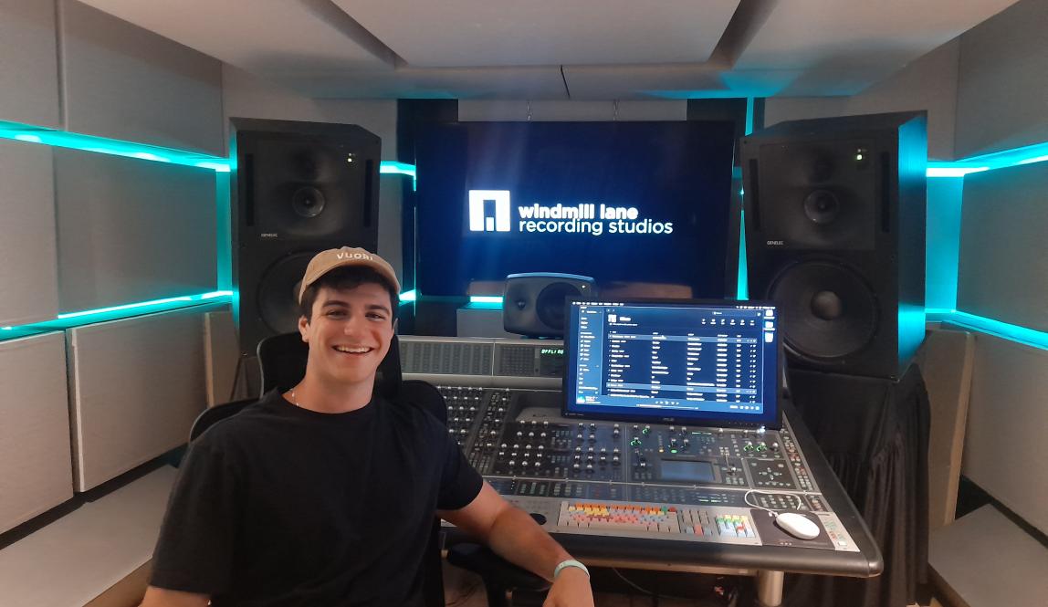 student smiling with hat on in front of audio visual equipment