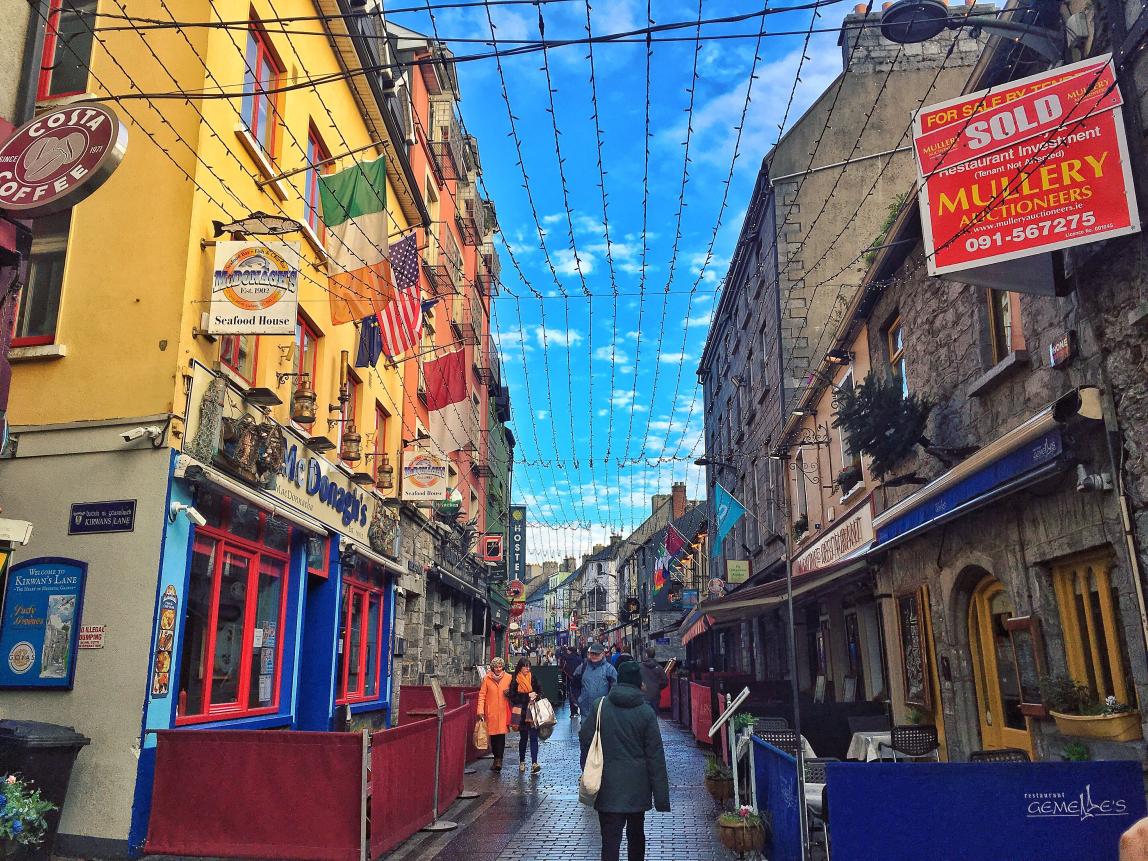 irish side streed at sunset lined with pubs, brick buildings, and a blue sky