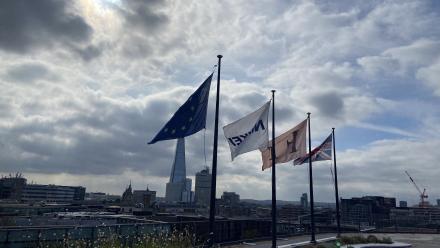 Three flags in the foreground of a view over the top of London's financial district