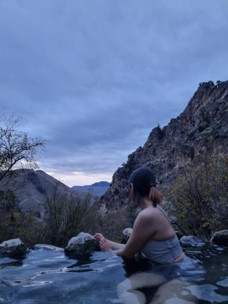 A student sits in the Montana hot springs at dusk
