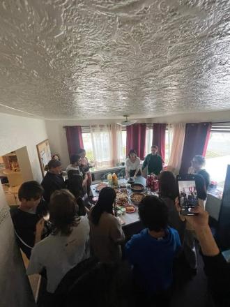 A group of University of Montana students gather indoors for a potluck