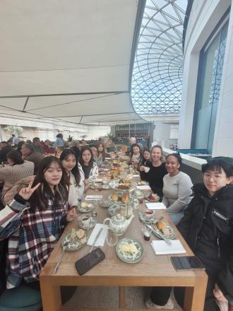 digital marketing students in London gather for afternoon tea around a wooden table  in a modern building