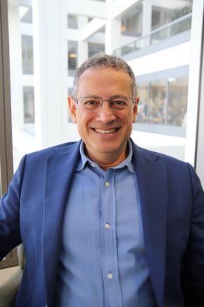 Headshot of Roberto Andreoni smiling against a window backdrop