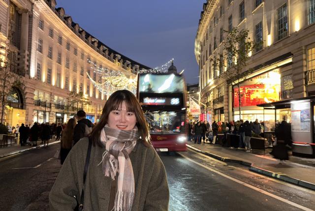 A student poses on the high street of Central London at night