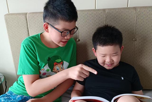 Staff member Gorden Xie's older son helping his younger brother read a book.