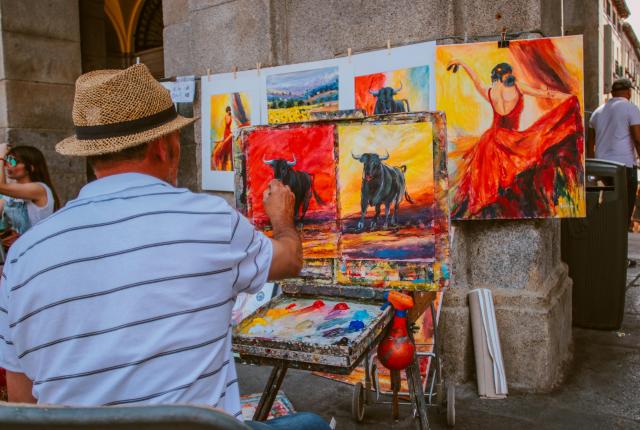 Painter on Spanish street working on paintings of bulls and Flamenco dancers